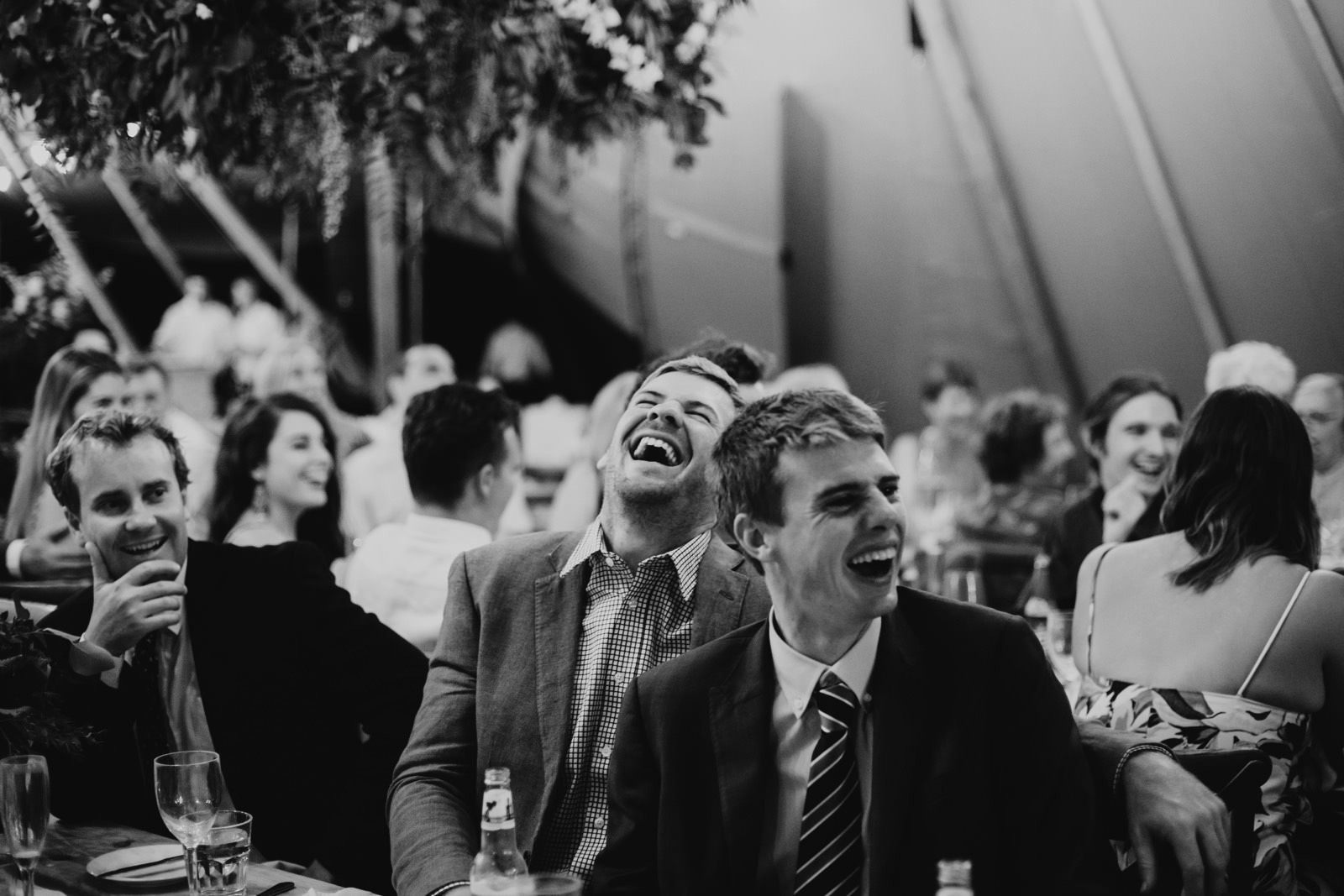 guests laughing at speeches at reception in tipi