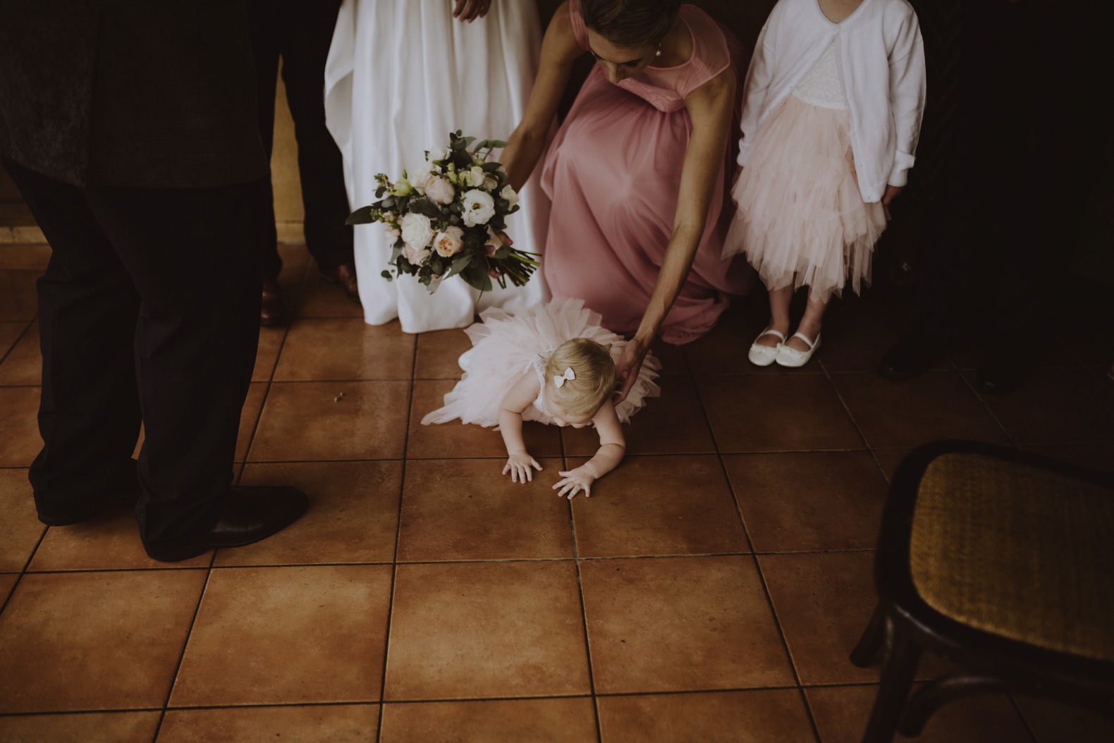 photo of little flower girl trying to crawl away during wedding ceremony