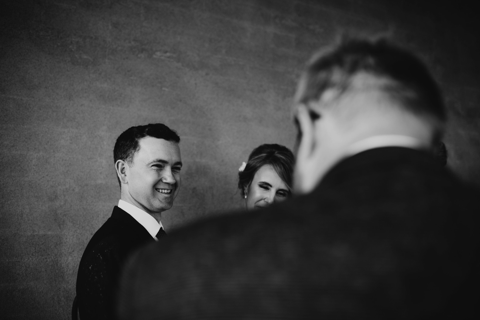 black and white photo of groom laughing during wedding ceremony