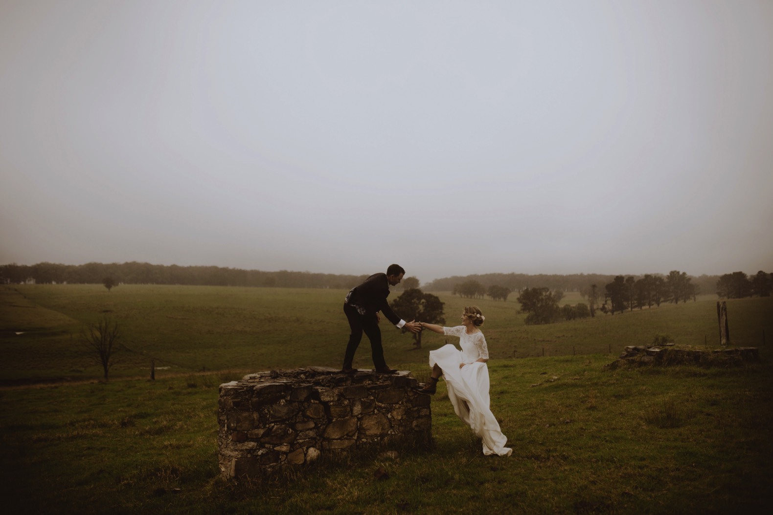beautiful countryside with rain and groom helping bride up