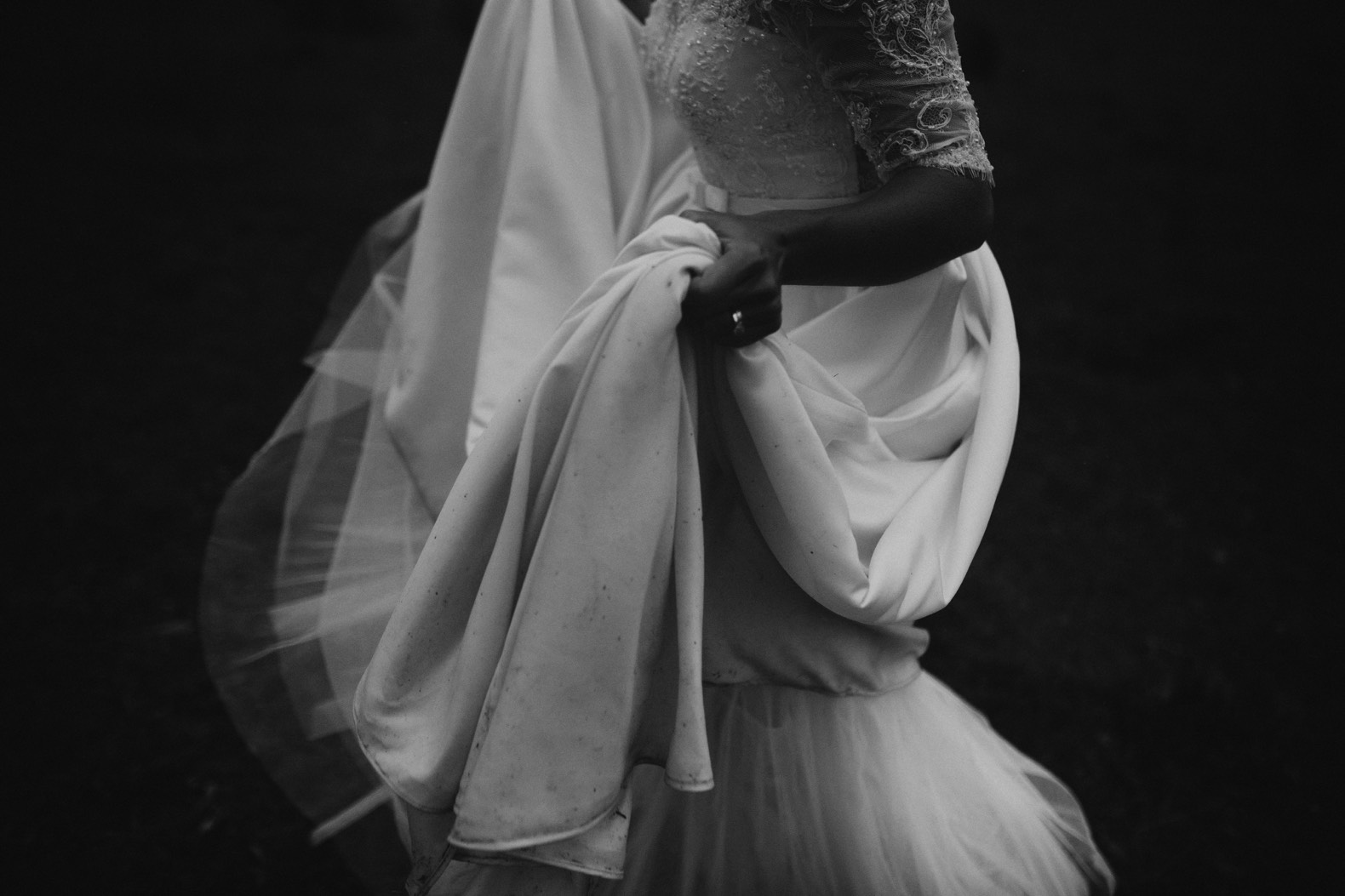 moody black and white photo of bride holding her wedding dress
