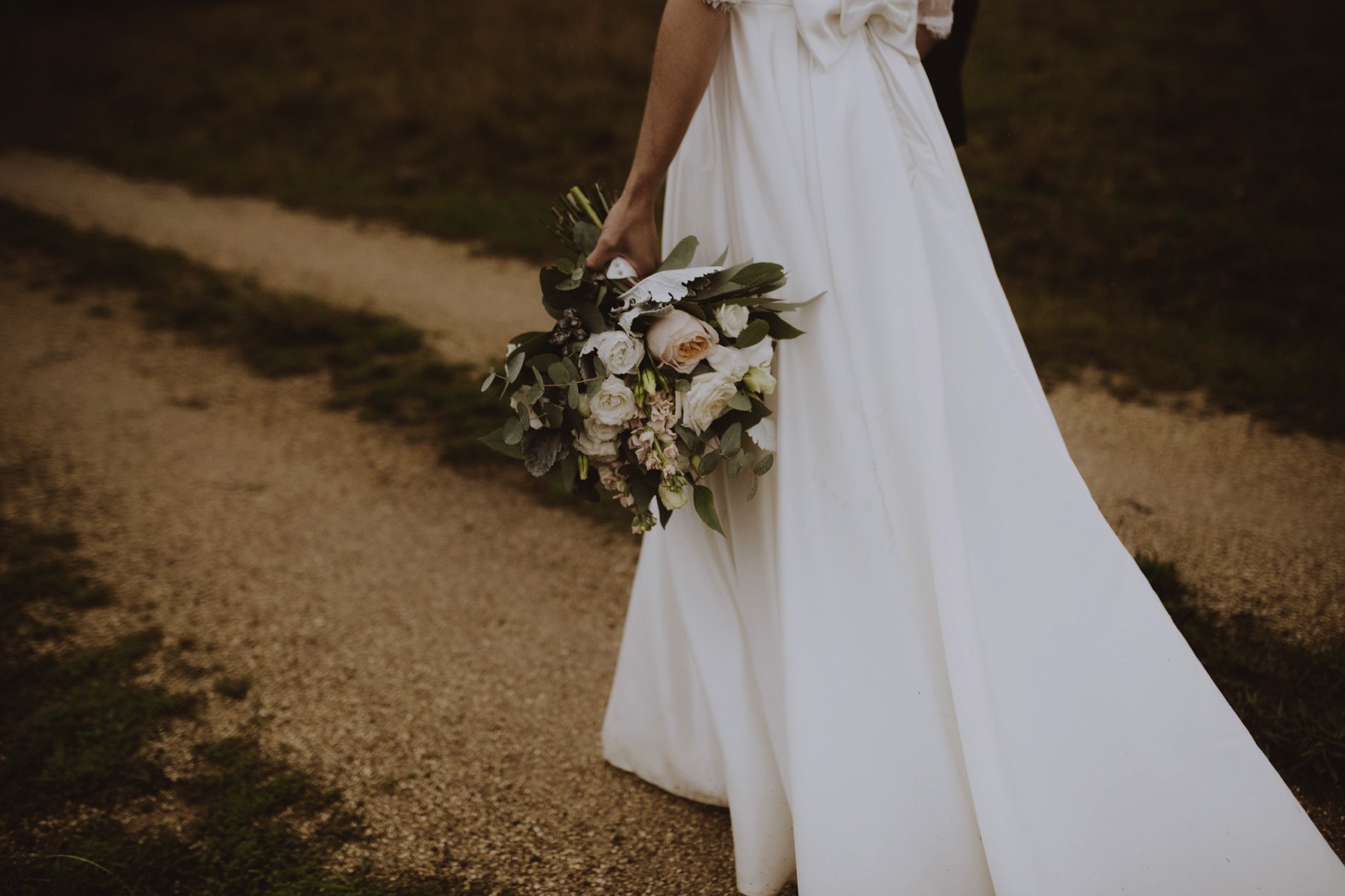 detail photo of bride holding flowers against her wedding dress